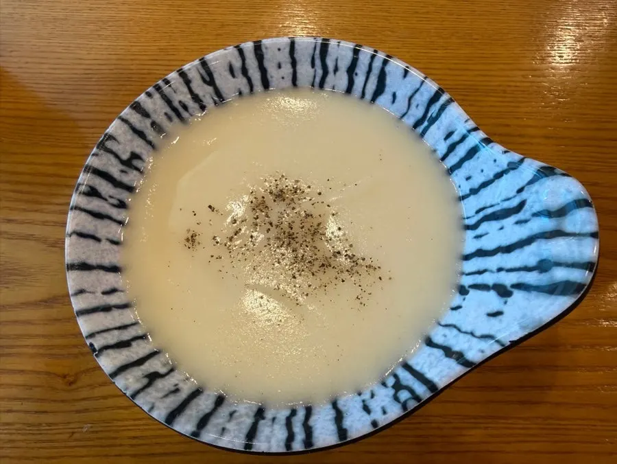A bowl of cream soup with pepper sprinkled on top