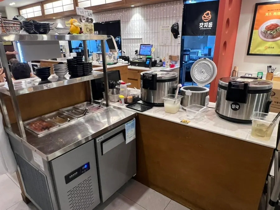 Dapur yang terlihat sedang memasak dan area tempat duduk meja