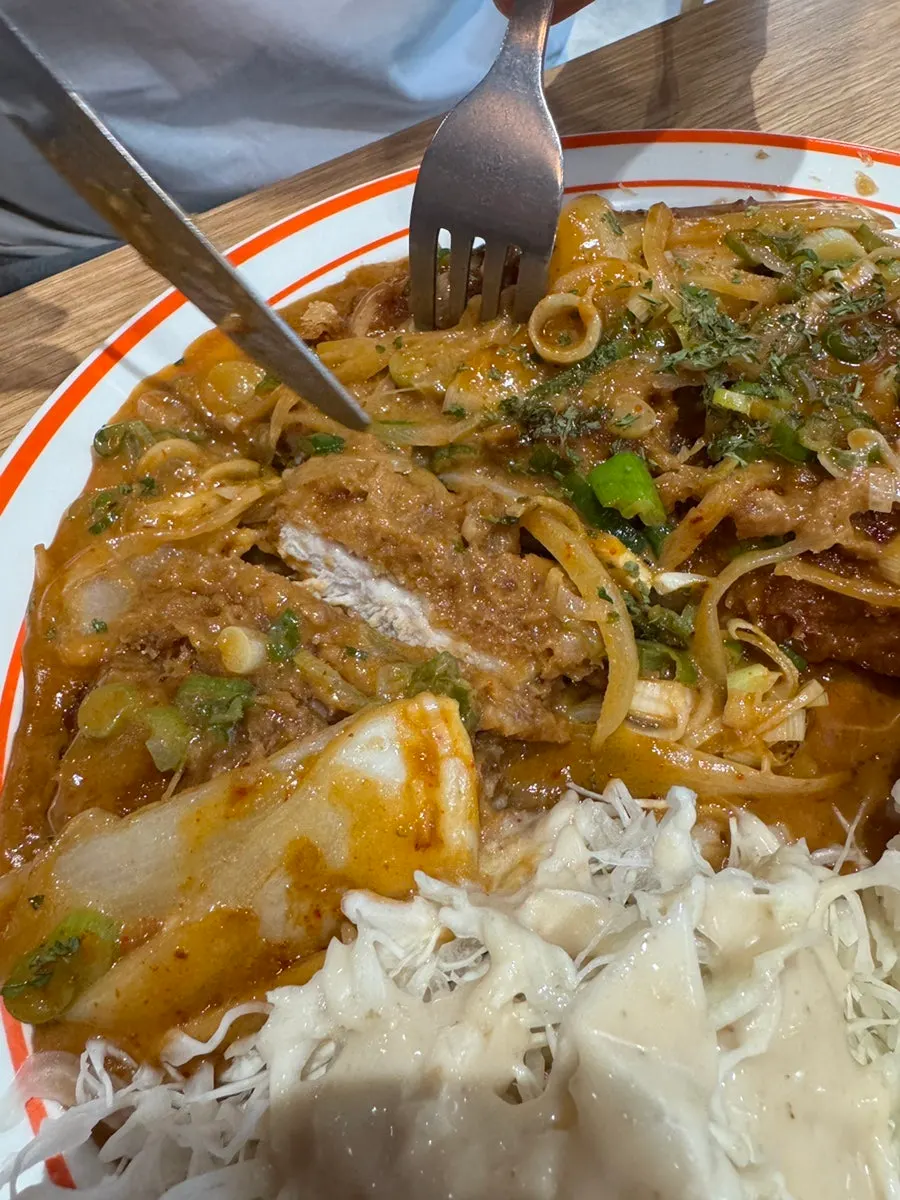 A piece of loin cutlet topped with onion and green onion