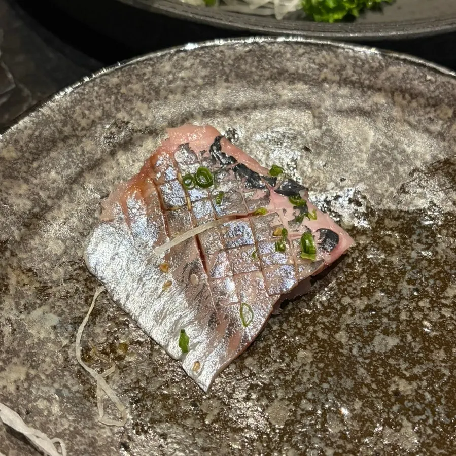 A piece of aged sashimi held with chopsticks