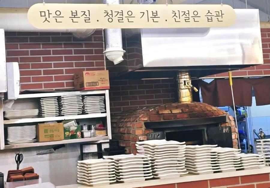 가야끝집 슬로건과 화덕이 보이는 매장 안쪽