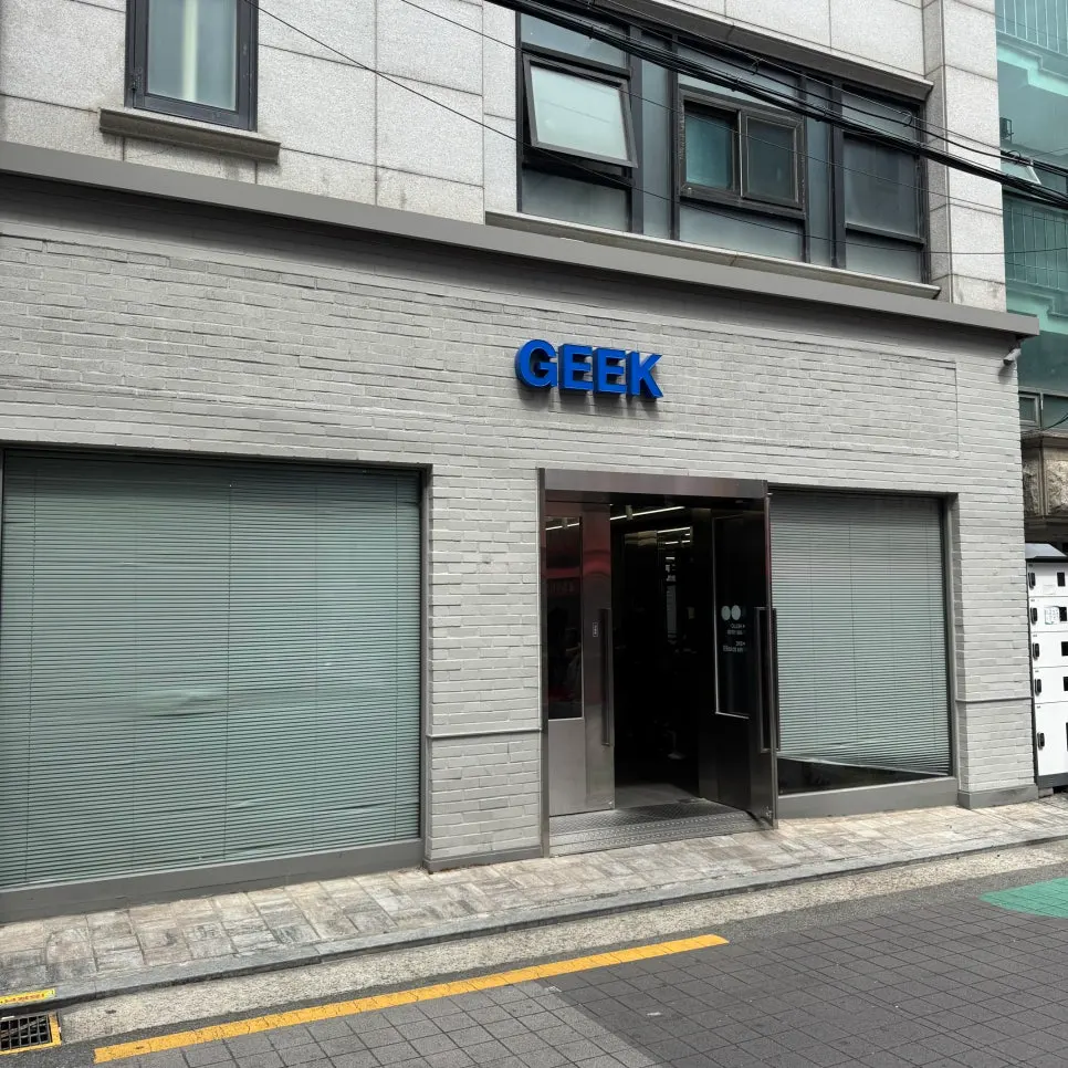 Exterior of Geek Hair Wangsimni with gray brick walls and a blue GEEK sign