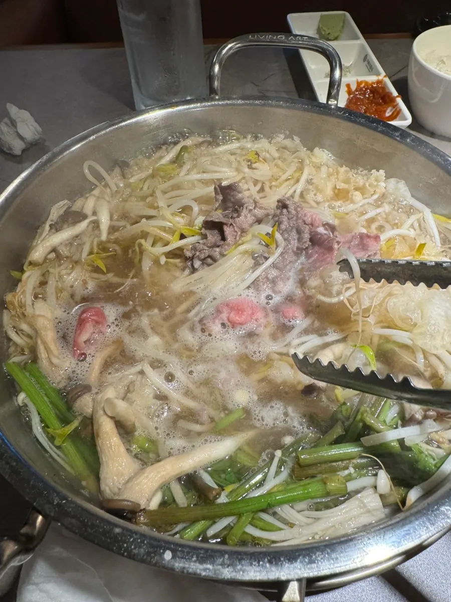 Pot of clear shabu-shabu loaded with minari and mushrooms