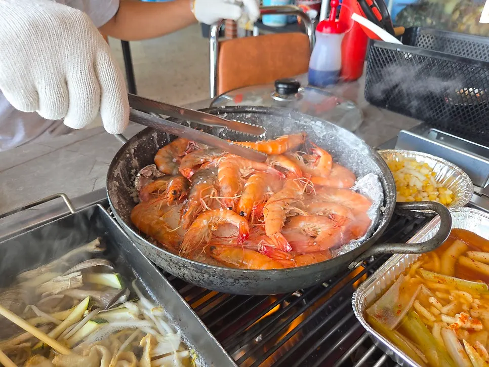Grilled shrimp being cooked evenly with tools