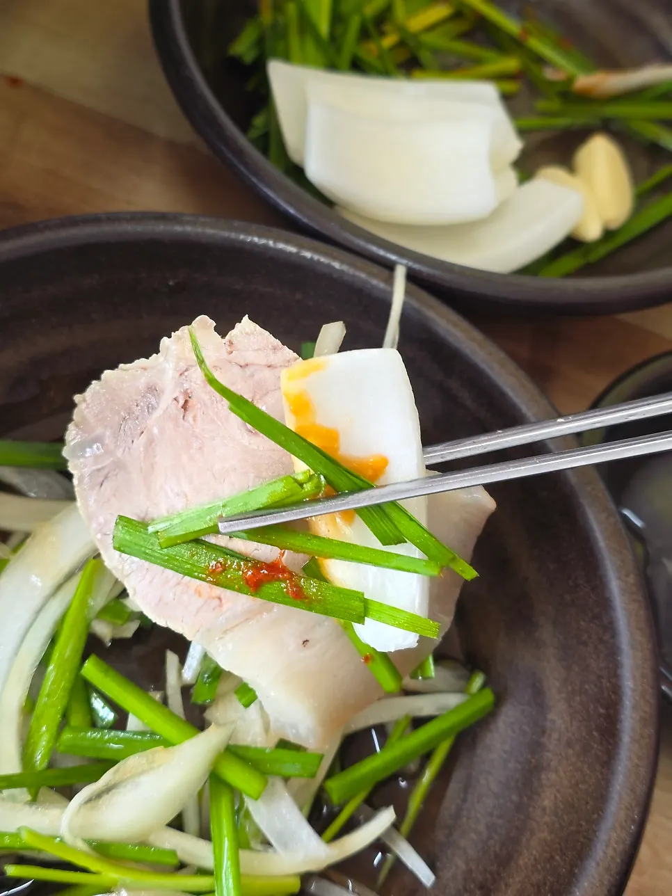 A piece of suyuk topped with chive-onion salad