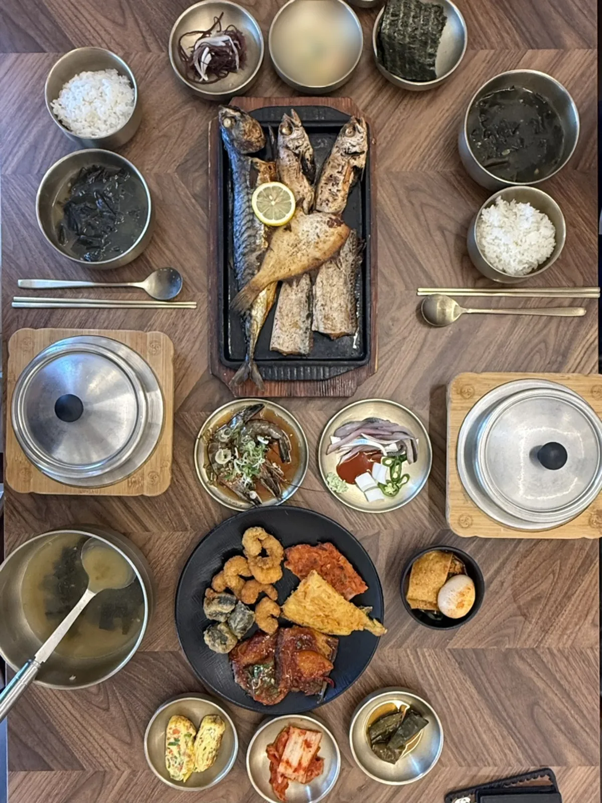 Table set for two with hot pot rice, grilled fish, and seaweed soup