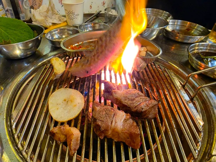 Pork belly grilling over charcoal briquettes