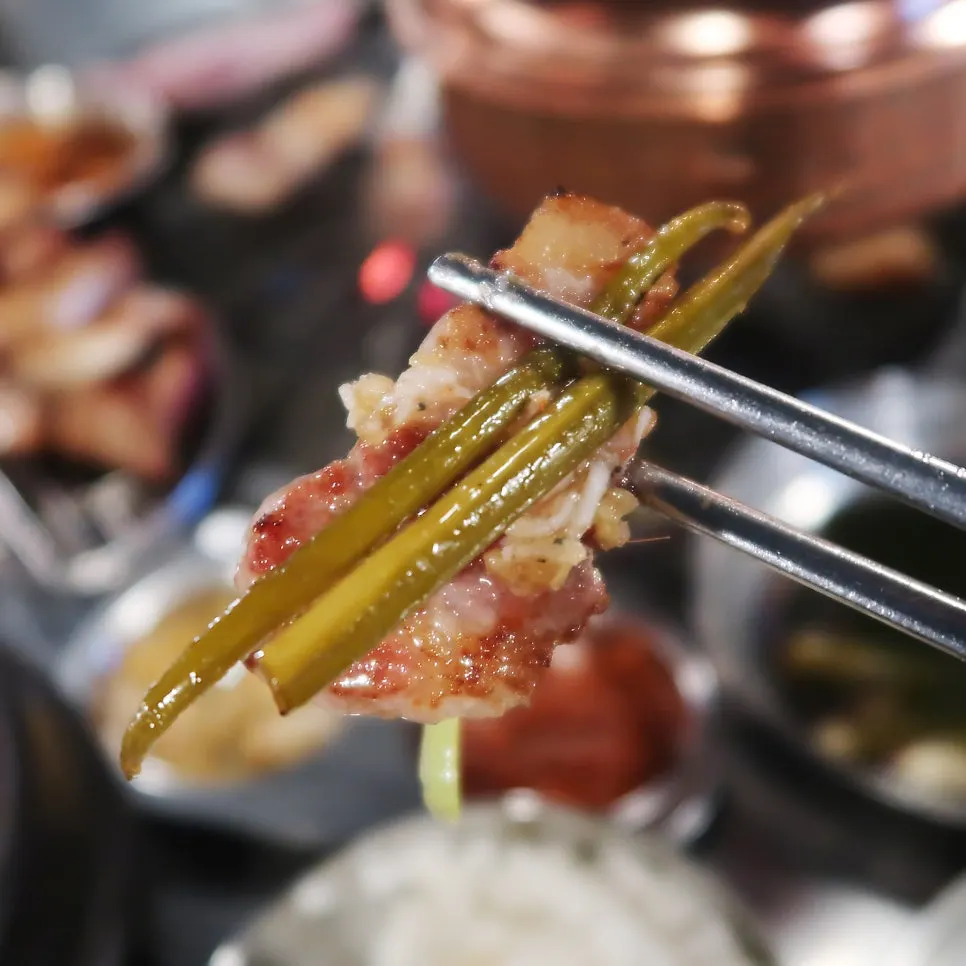 불판에서 익은 돗갈비와 마늘쫑장아찌