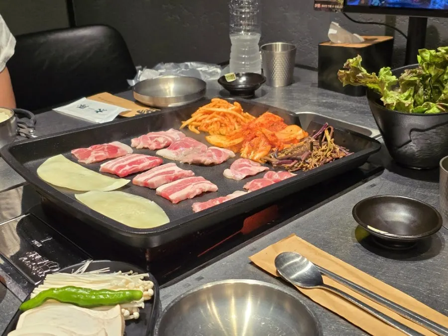 Pork belly, mushrooms, and sour kimchi grilling on the plate