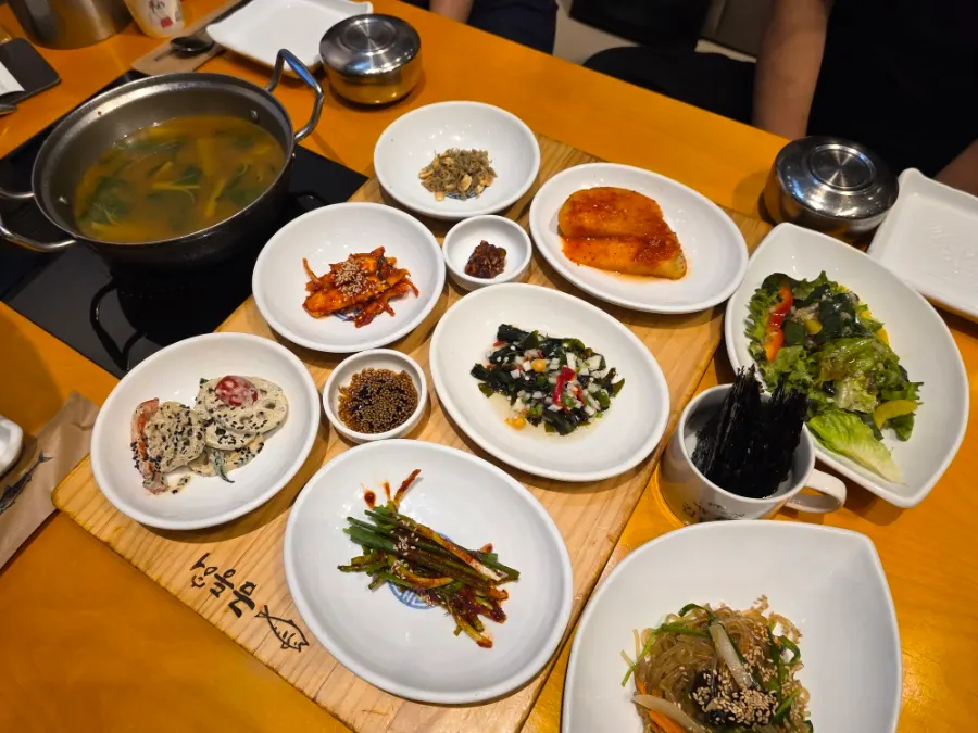 Plates of lotus root and seaweed salad among the banchan