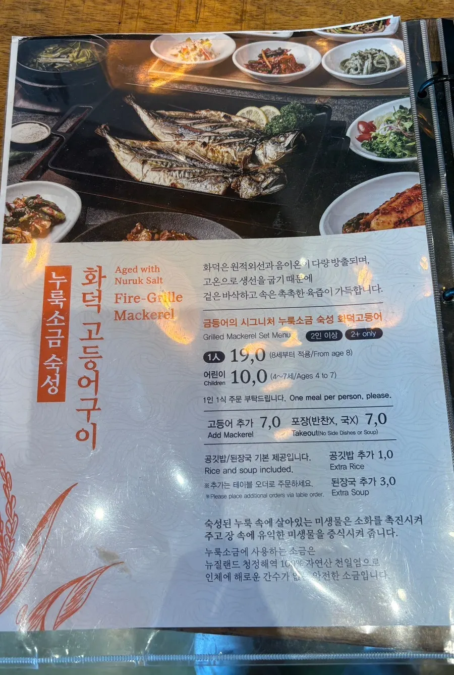Menu board showing prices for fire-grilled spicy pork and cockle salad