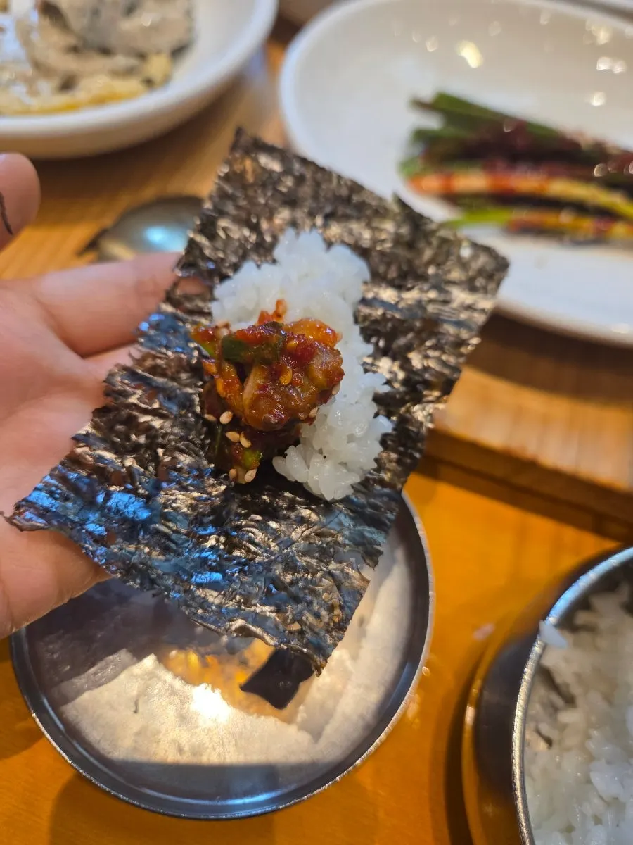 A bite of rice topped with cockle salad