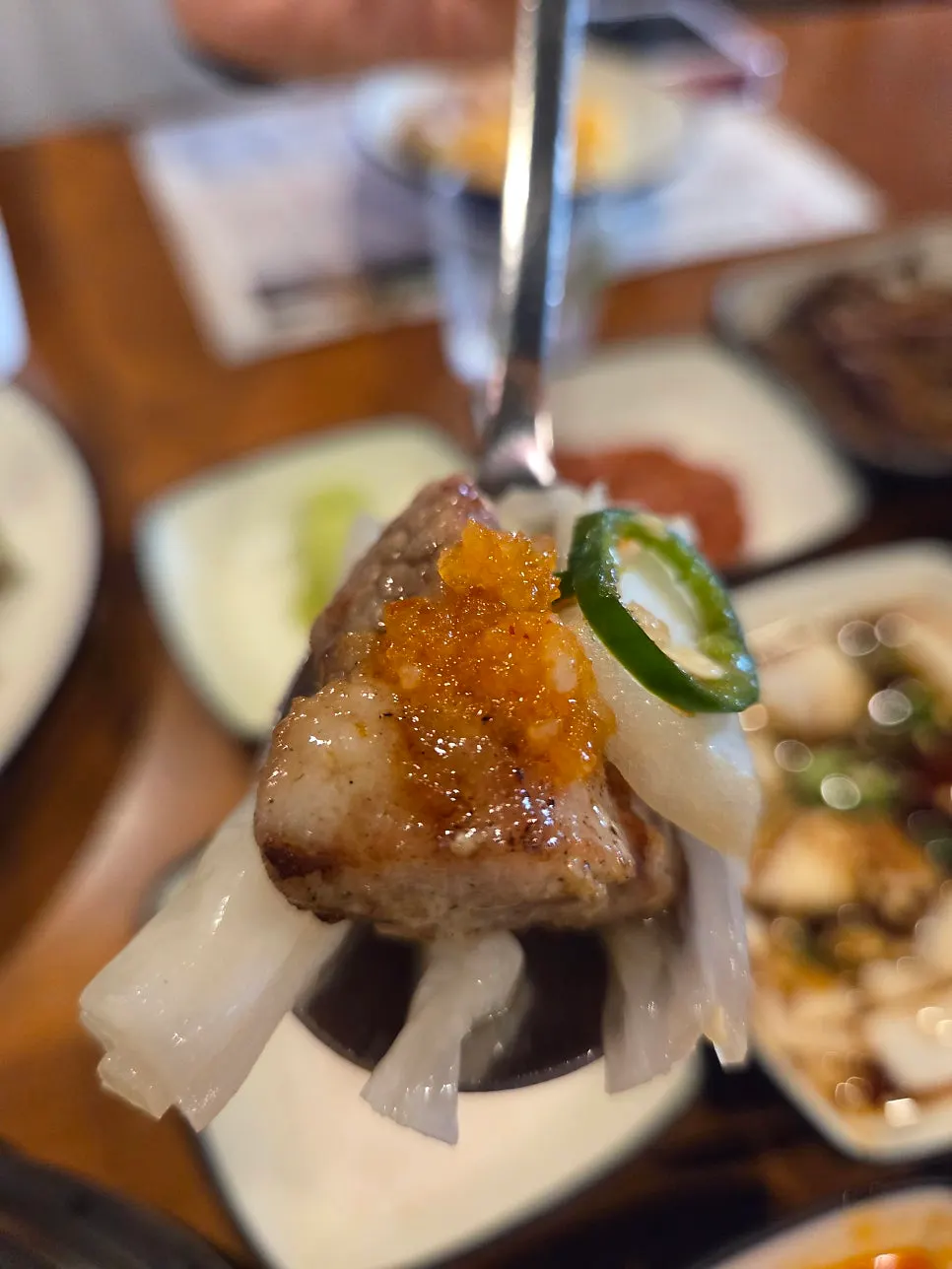 Pork belly topped with grilled baek-kimchi and pickled onion