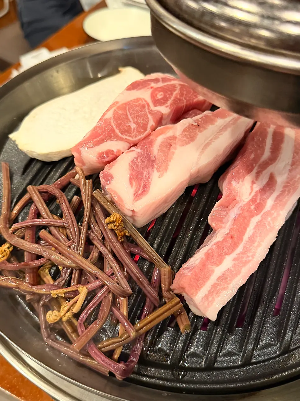 불판 옆에서 함께 구워지는 고사리와 버섯