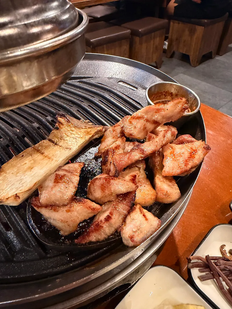 불판 옆 돌판에 올려둔 익은 고기와 버섯