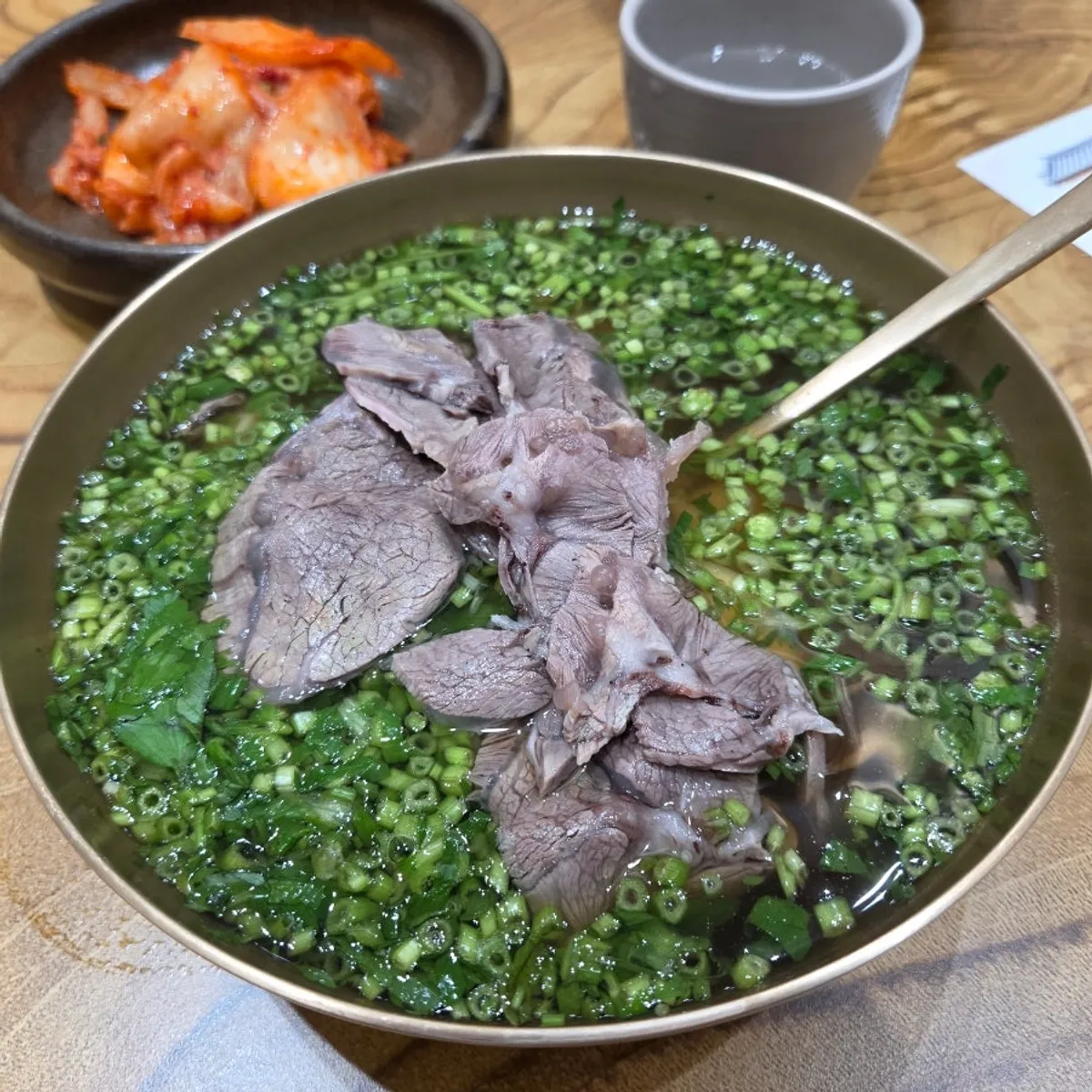 A bowl of minari gomtang generously filled with Korean beef