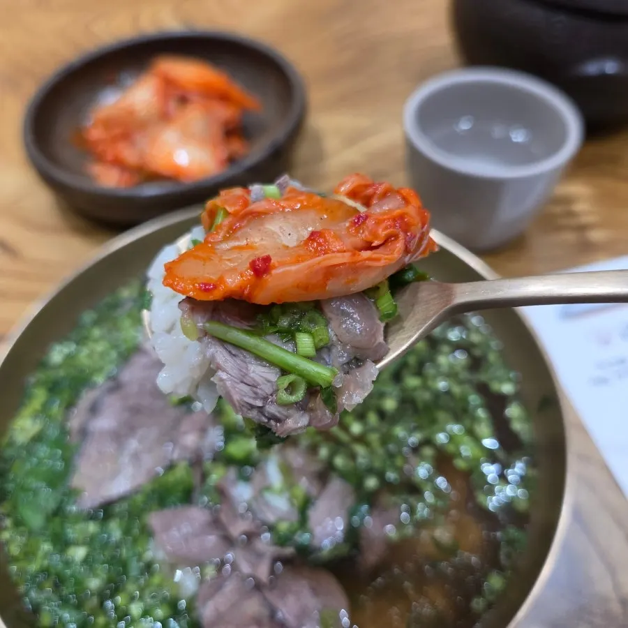 A spoonful of gomtang with finely chopped minari