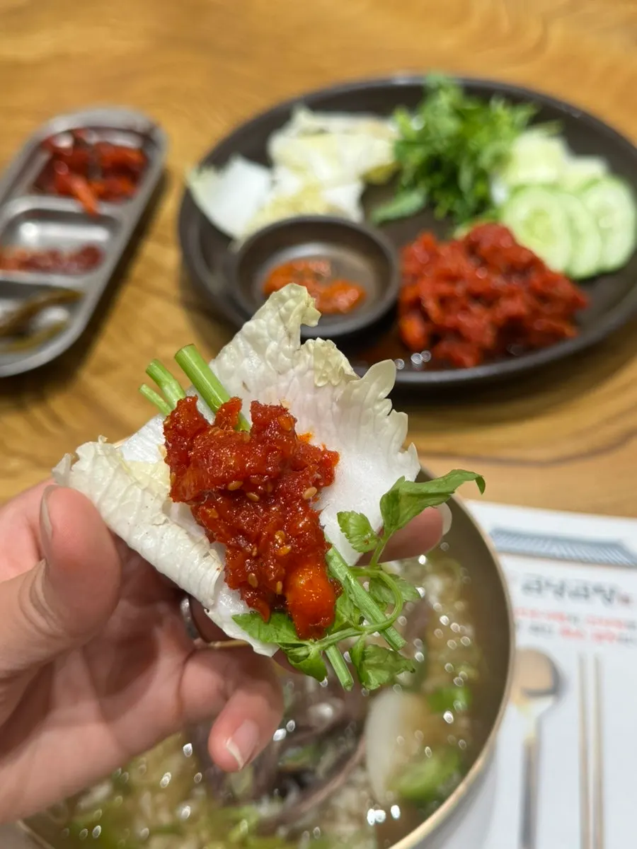 A cabbage wrap topped with minari and pollock salad