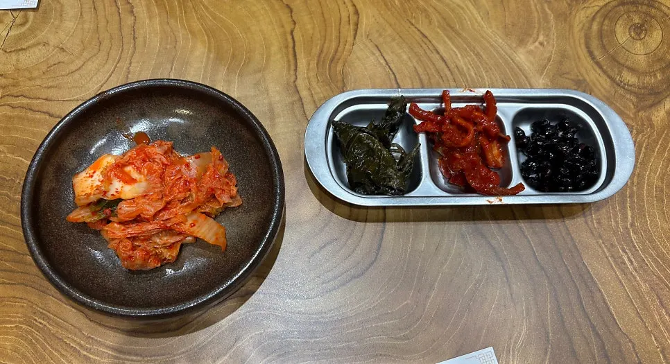 Piring berisi oi gochu, kacang kedelai, daun perilla, dan banchan lainnya