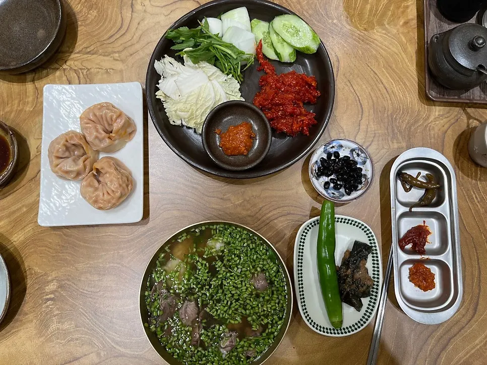Table setting with minari gomtang, pollock salad, and kimchi dumplings