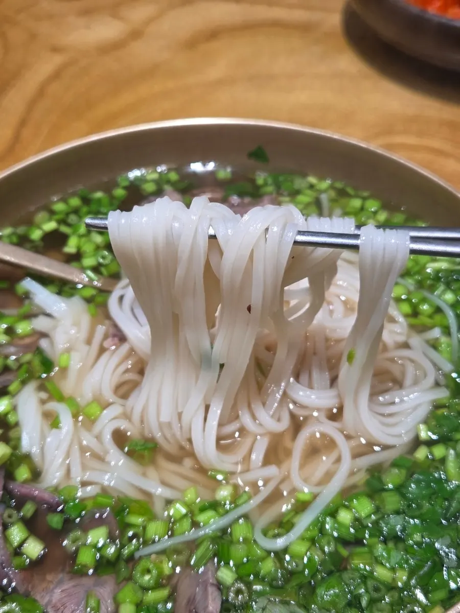 Scooping up minari and shredded meat together in minari gomtang