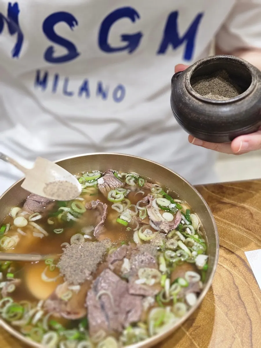 A bowl of special gomtang served with a spoon stuck in it