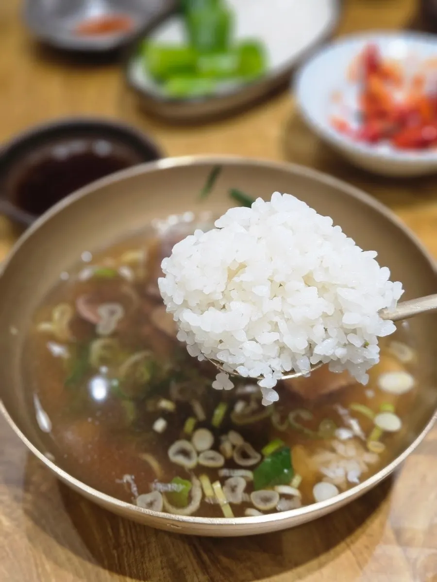 A table spread with rice and self-serve banchan
