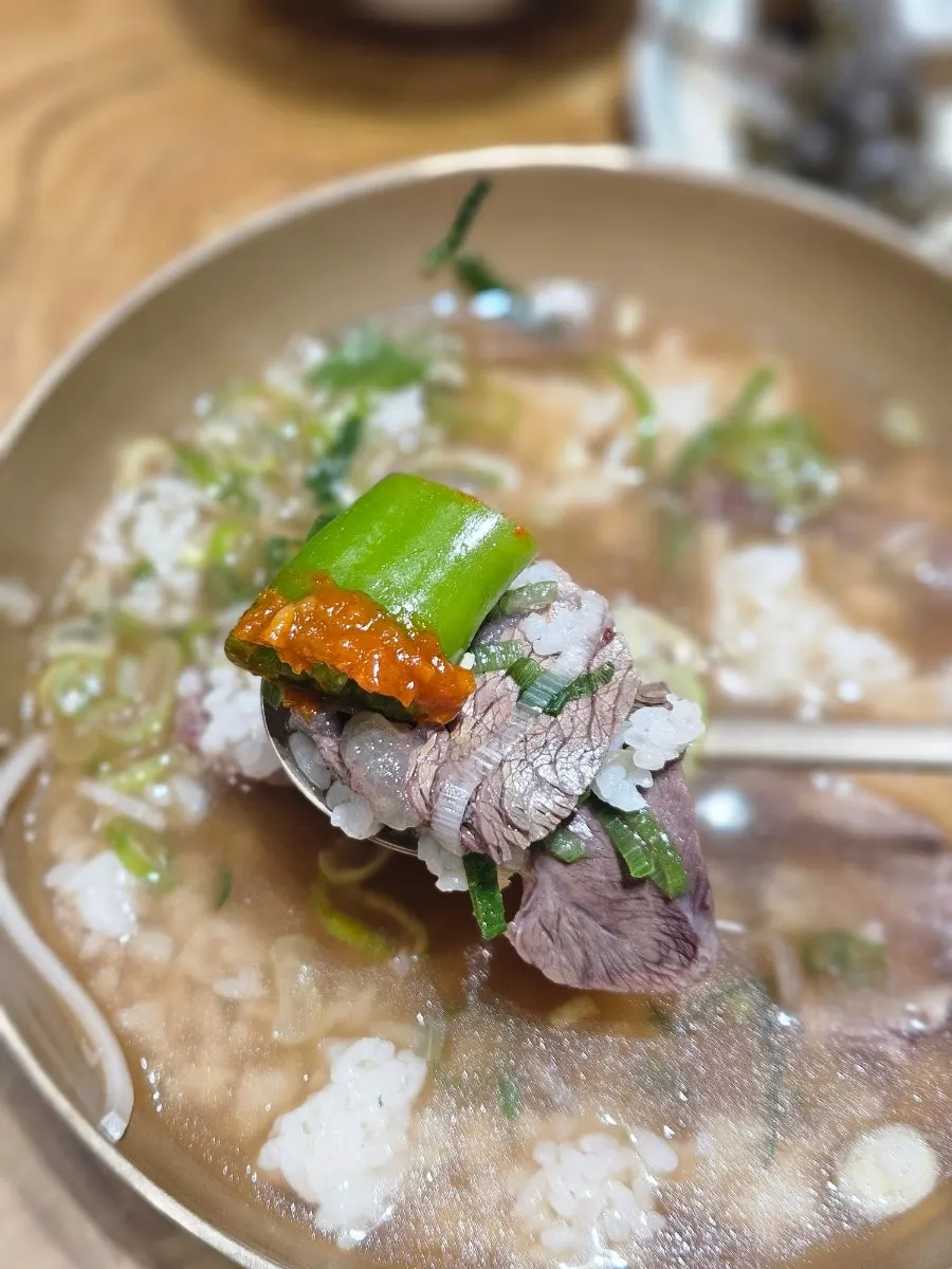 A spoonful of the broth with mixed-in rice