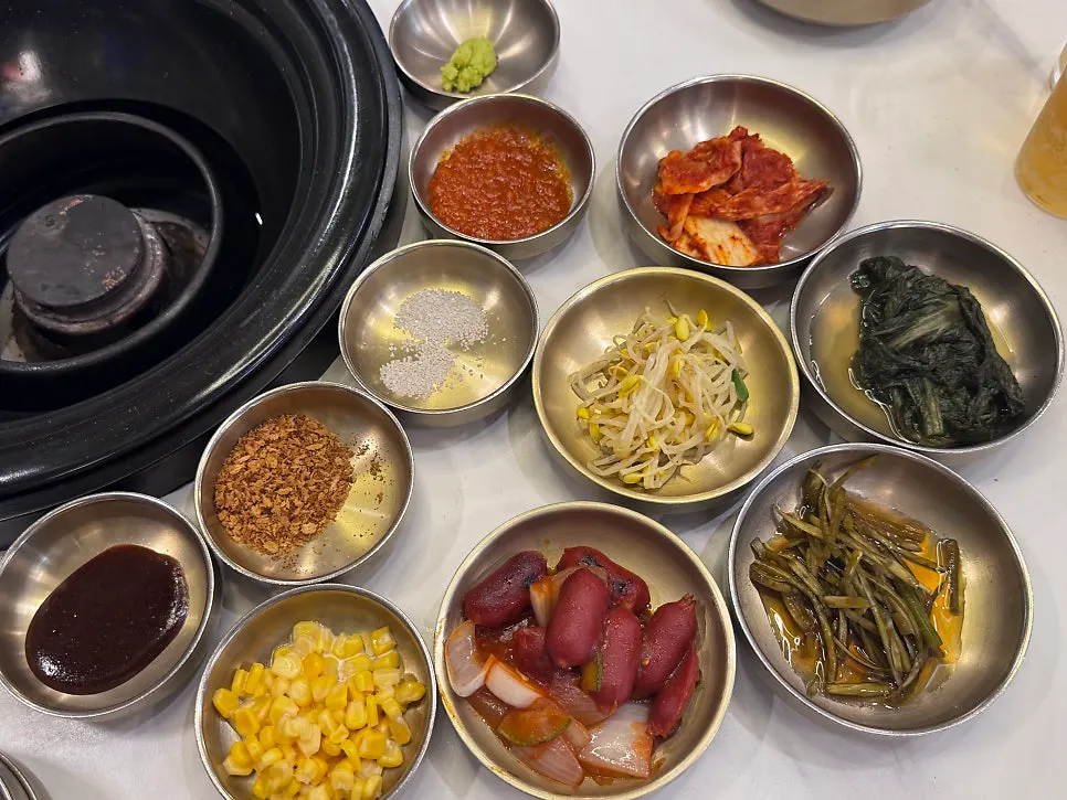 A spread of side dishes including kimchi, seasoned bean sprouts, and corn salad