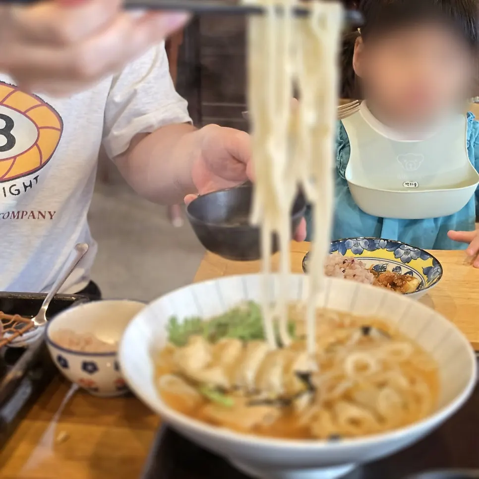 Lifting up a forkful of udon noodles