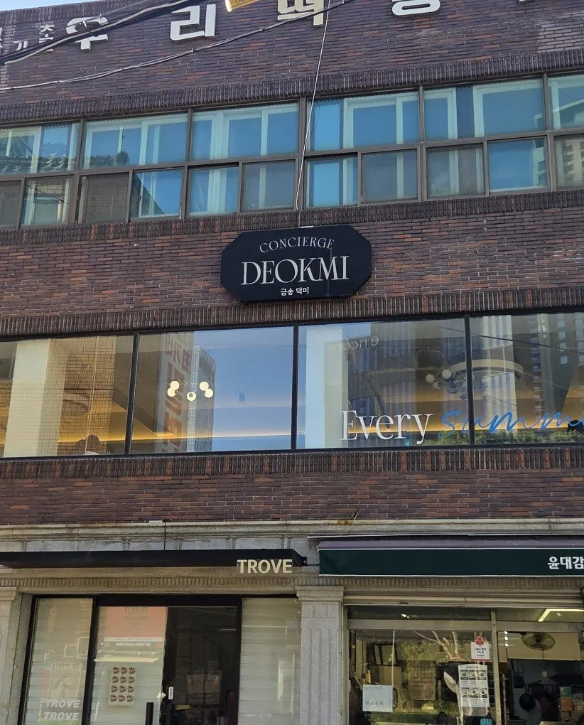 CONCIERGE DEOKMI 간판이 달린 벽돌 건물 외관