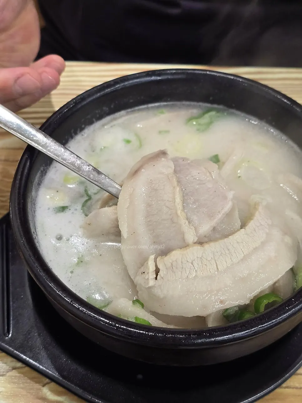 A piece of pork jowl lifted out of the soup