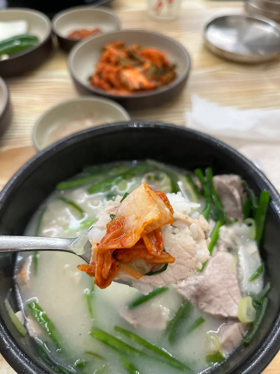 국수와 김치를 올린 돼지국밥 한 술