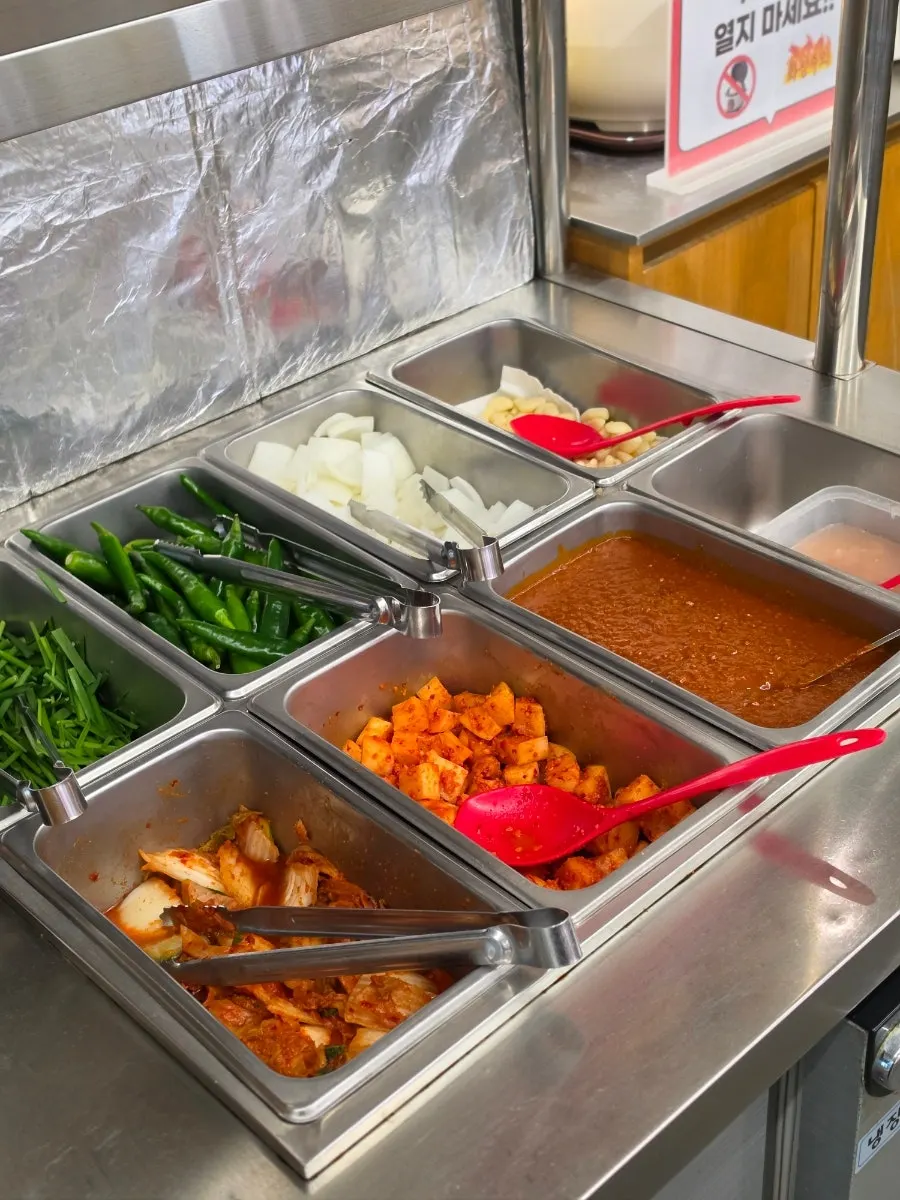 Self-serve bar with chives and kimchi at Geumsu Dwaeji Gukbap