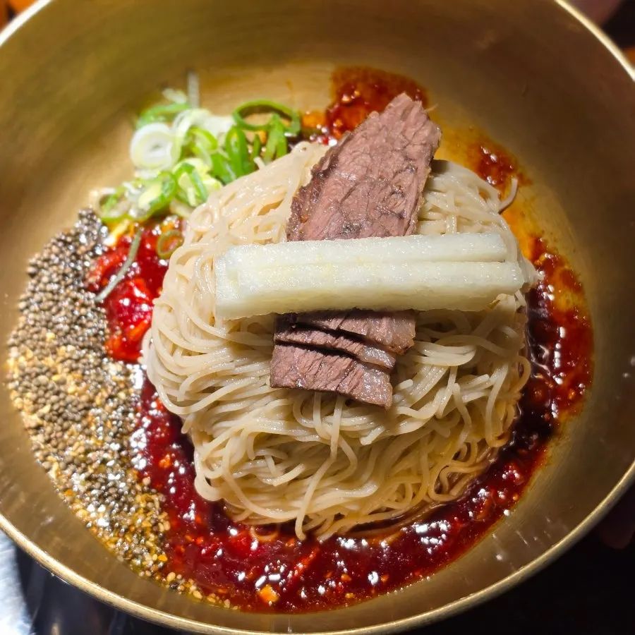 Perilla oil bibim naengmyeon topped with whole perilla seeds and pear
