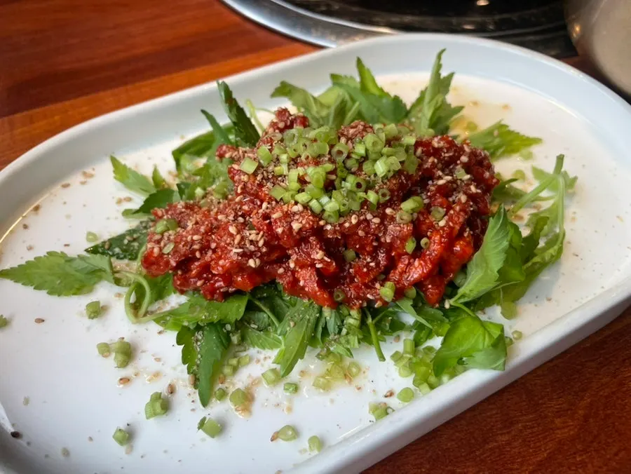 A plate of yukhoe topped with minari