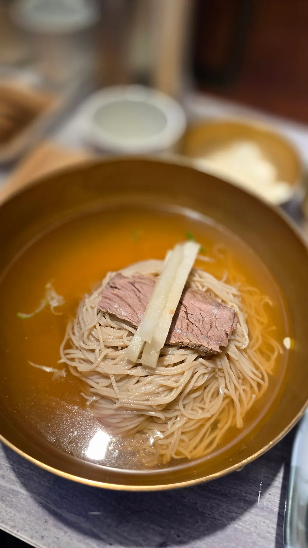 Vertical photo of a bowl of pyeongyang naengmyeon at Geuni Sikdang