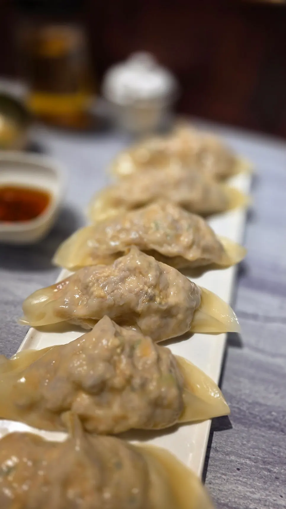King mandu cut in half showing the filling, with a soy sauce dish