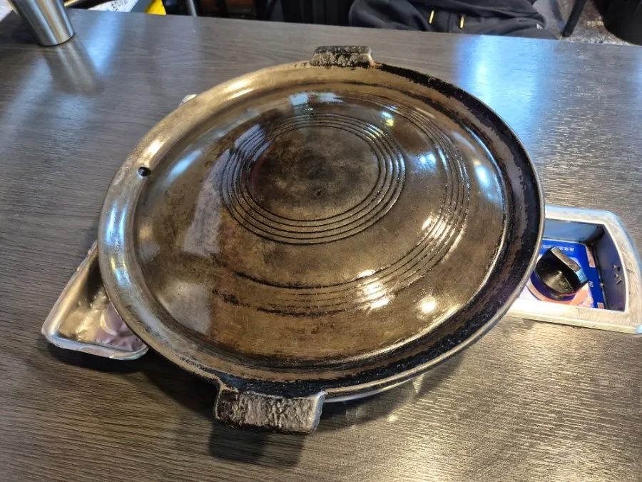 Well-oiled, shiny cauldron-lid grill