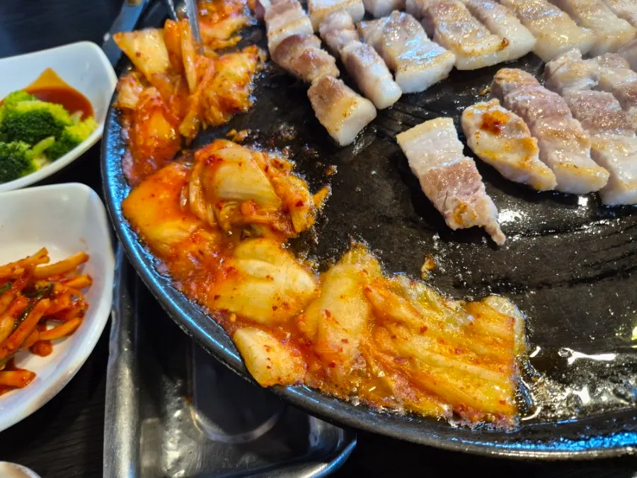 Aged kimchi placed on the oil-runoff side of the grill