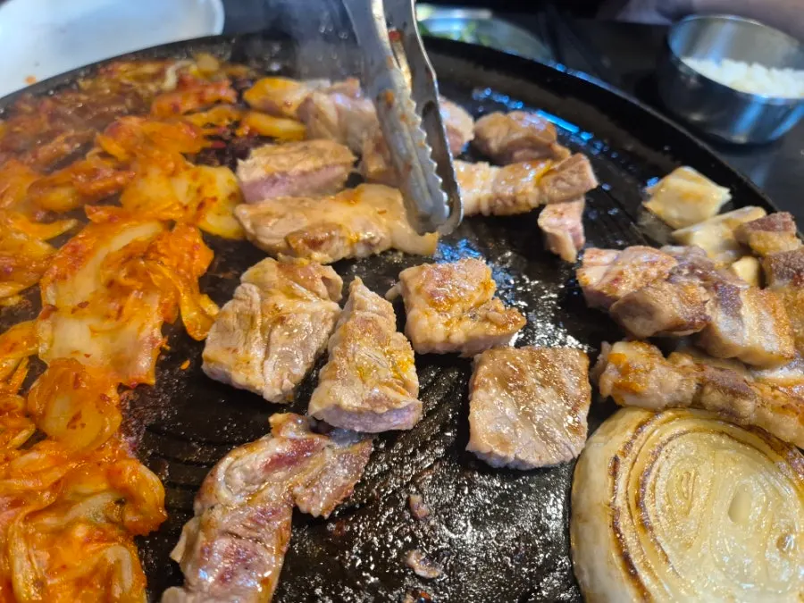 Pork neck and kimchi grilling on the cauldron lid