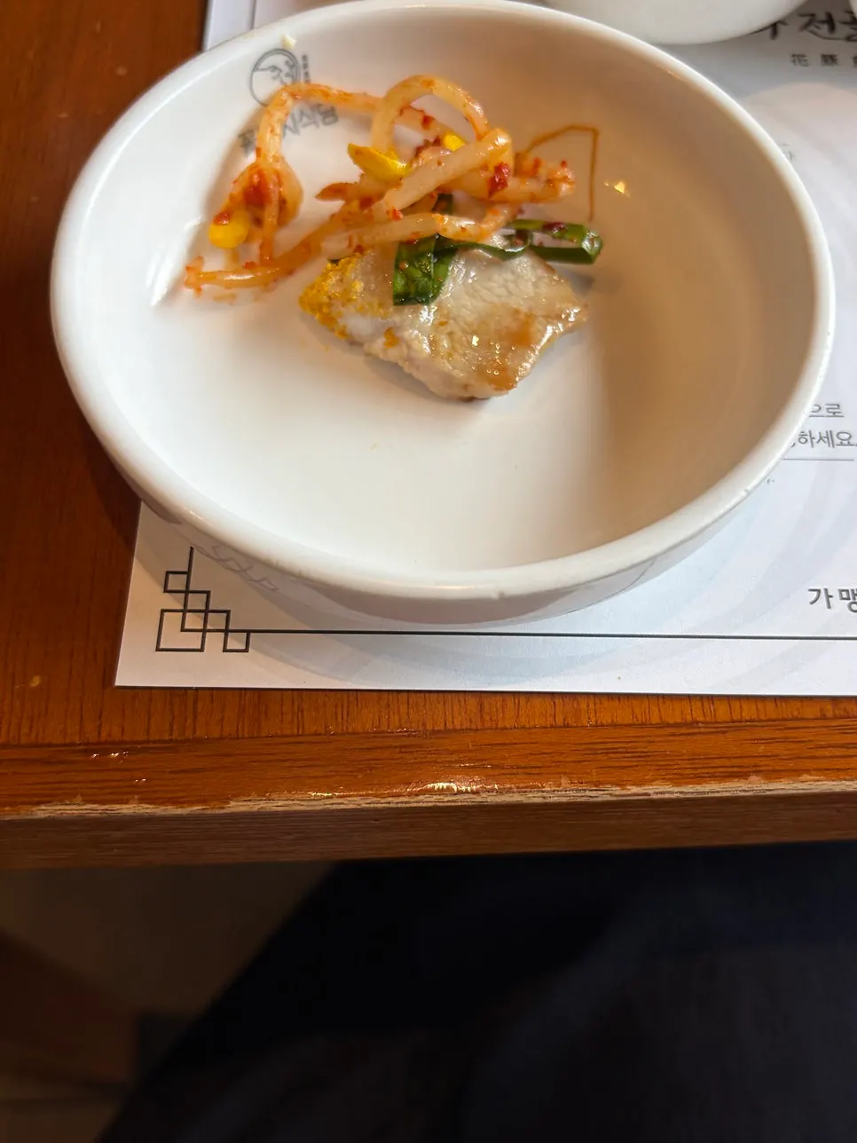 A piece of pork jowl with bean sprouts, chive kimchi, and sauce