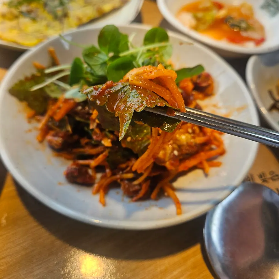 A bite of seasoned cockles and bibimbap