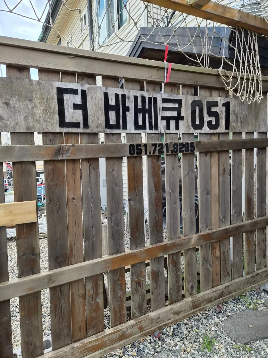 Pintu masuk dengan pagar kayu dan papan nama The Barbecue 051