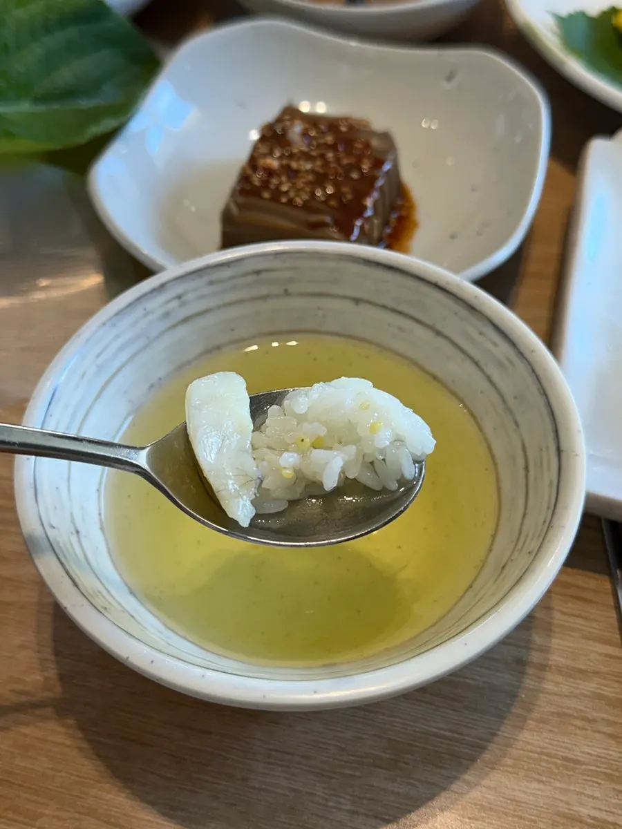 A spoonful of rice soaked in green tea water topped with dried corvina