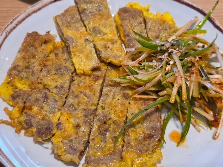 A plate of beef jeon served with scallion salad
