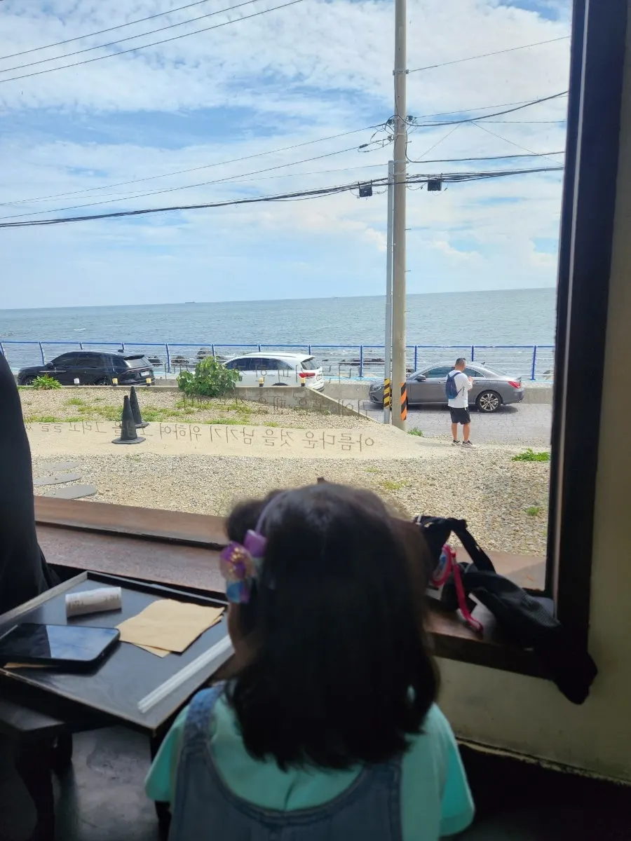 Interior seating at Deokmi Gijang Branch with the sea visible through floor-to-ceiling windows