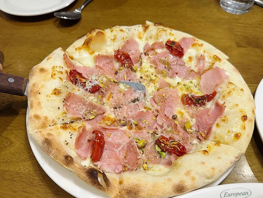 Jambon pizza topped with honey and pistachio