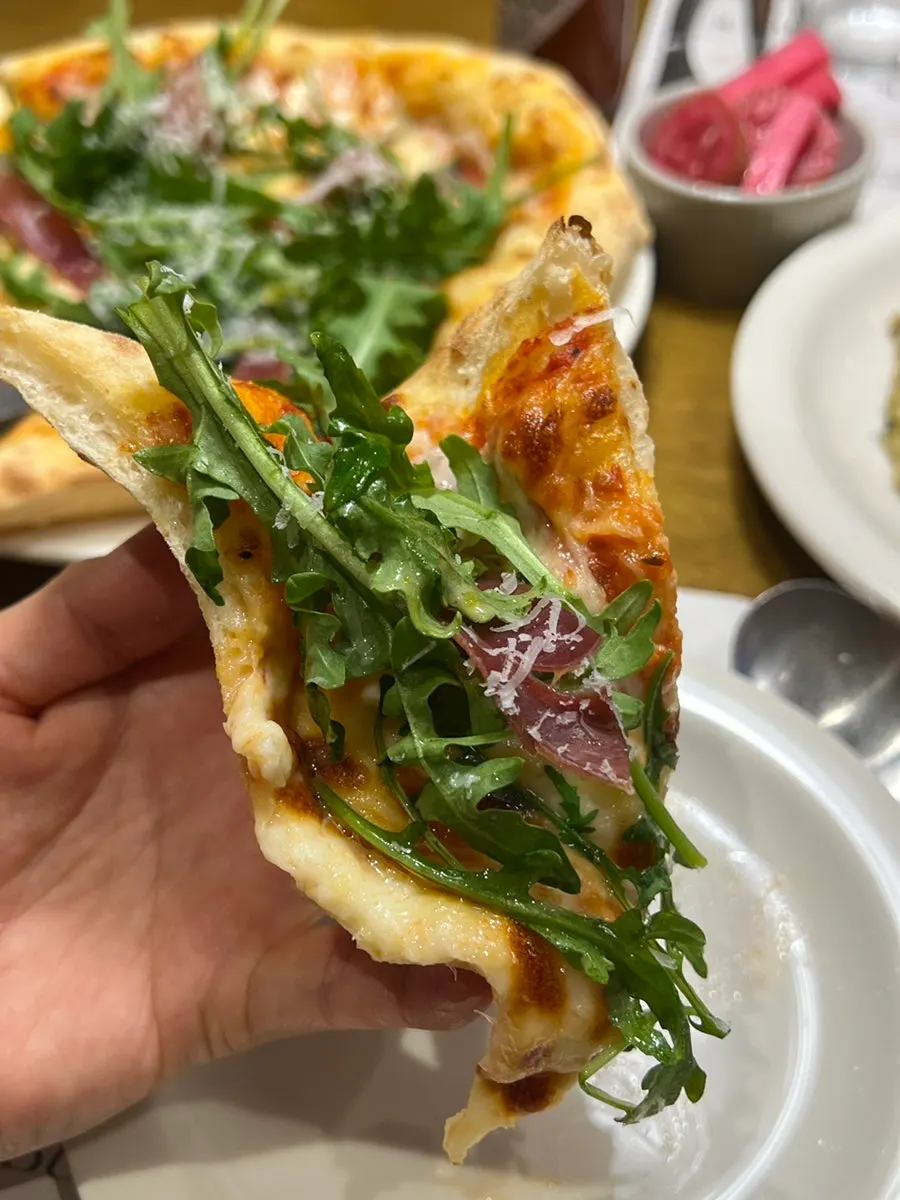 A slice of pizza piled high with arugula