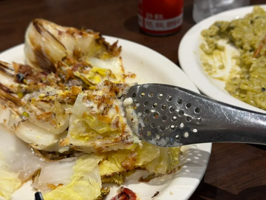 Grilled napa cabbage salad topped with bacon chips and cheese